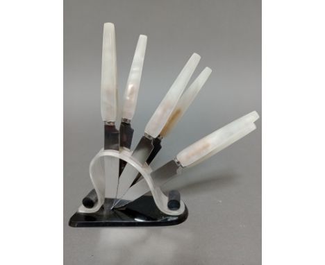 An Art Deco marble effect and black bakelite knife stand with six knives, the serrated steel blades marked 'Rostfrei Solingen