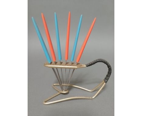 A vintage gilt metal knife stand with rubber bound handle and six multi-coloured plastic handled knives, the serrated steel b