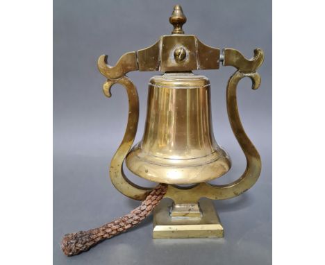 A brass bell with rope, mounted on a brass stand. 