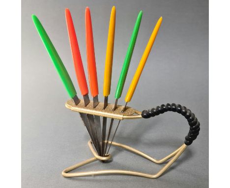A vintage gilt metal knife stand with rubber bound handle and six multi-coloured plastic handled knives, the serrated steel b