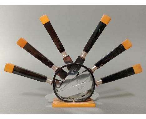 An Art Deco black and butterscotch bakelite knife stand with six knives, the steel blades marked 'Rostfrei Solingen'. 