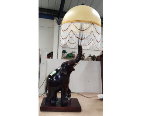 A large carved elephant table lamp with Art Deco style tasselled shade 
