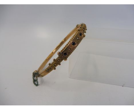 A 9ct gold bangle inset with sapphires and a seed pearl, weight approx. 8g.