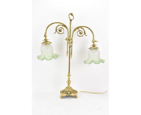 An early 20th century brass adjustable table lamp, having two branches with opalescent green shades, applied scroll work moun