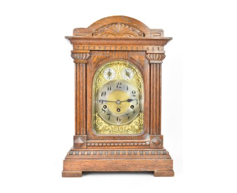 A circa 1900 oak cased mantle clock, the case of architectural form with an arched top, dental moulded cornice and two reeded