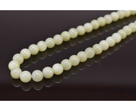 A pale green jade bead necklace, 20th century, of uniform size and near uniform colour, strung to a plain white metal clasp, 