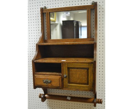 An early 20th Century oak bathroom medicine cabinet, rectangular mirror over an arrangement of shelving, towel rack to base (