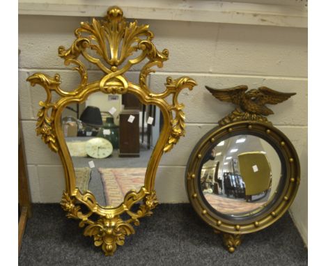 A reproduction gilt framed circular mirror, the frame mounted with spheres and surmounted by an Eagle; another, Rococo-style 