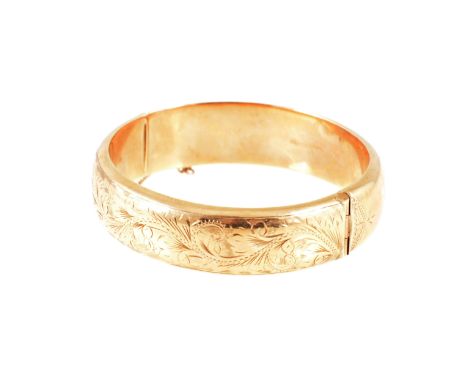 A 9 carat yellow gold 15mm wide hollow half hinged bangle, scroll decoration to front, approximate weight 23.9gms.