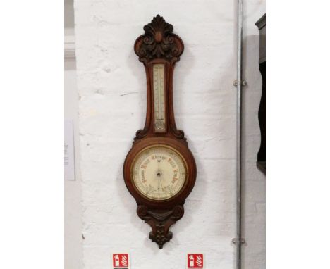 A carved oak aneroid banjo shape barometer, circular dial with thermometer over, case with scrolled outlines, 91cm.
