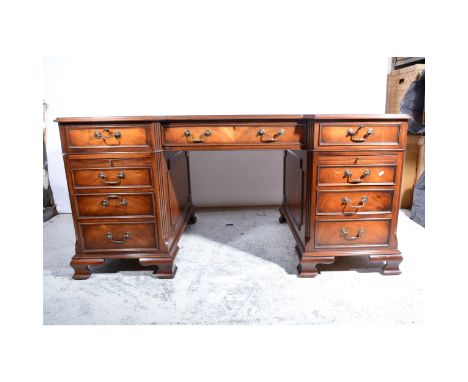 Reproduction mahogany desk, double faced, with a recessed centre, three tooled leather panels to the top, fitted with a friez