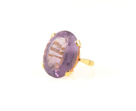 A large amethyst dress ring, the oval step cut stone 22mm x 15mm x 9.5mm, approximate carat weight 15.5cts, four claw set in 