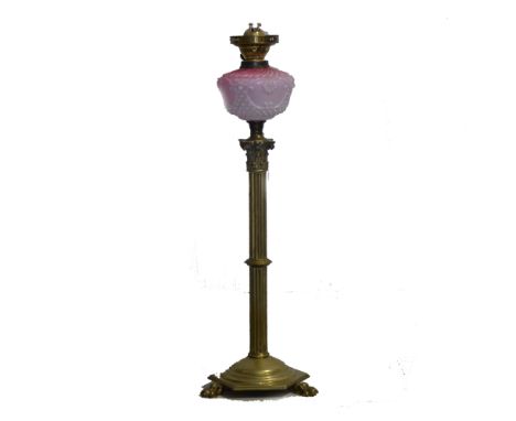 Edwardian brass oil lamp, pink opalescent reservoir, Corinthian column raised on three claw feet, 79cm high.