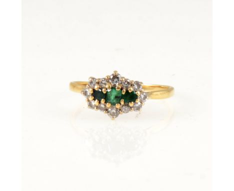 An emerald and diamond cluster ring, three small emeralds claw set horizontally and surrounded by twelve brilliant cut diamon