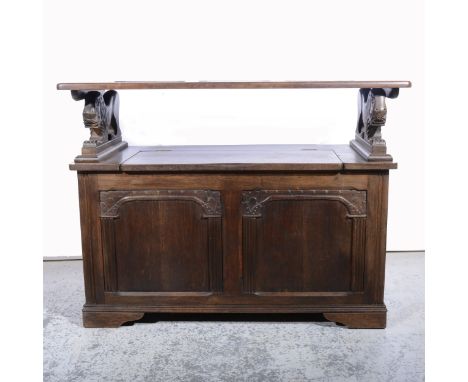 Oak and stained wood monks bench, with a flap-over table top, with hinged box seat, with lion shaped uprights, two panels und