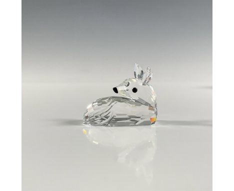 A clear faceted figure of a young deer laying down. Part of the Woodland Friends collection. Swarovski marking. This item has