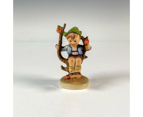 A figure of a child wearing a blue jacket and green hat resting on an apple fruit tree. M.I. Hummel. Goebel backstamp. Dimens
