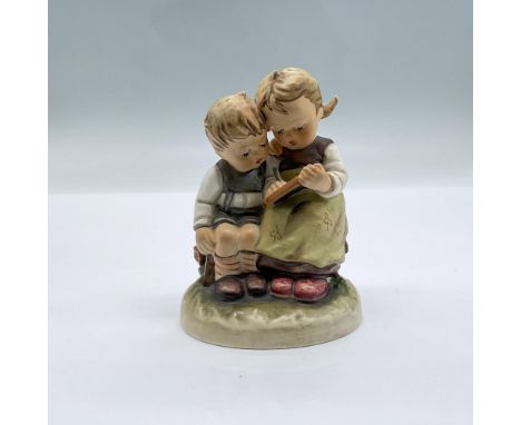 An adorable porcelain figurine of two young children sitting on a bench. The little girl is teaching the young boy his A B C'
