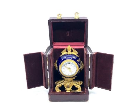 Small travel clock, in original leather case, desplate inscribed on small enamel dial, contained in a blue enamelled case, ca