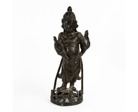 A CHINESE BRONZE FIGURE OF A GUARDIANMing dynasty Modelled standing with one hand on hip, wearing uniform and helmet, raised 