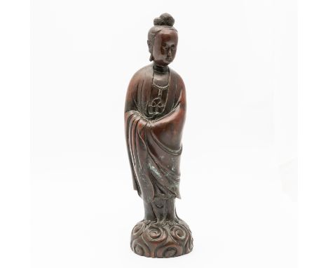 A CHINESE SILVER-INLAID PATINATED BRONZE FIGURE OF GUANYINQing dynasty The goddess cast standing on scrolls in long flowing r