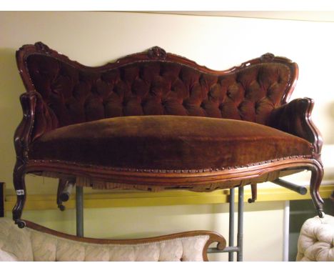 A Victorian style spoon back sofa with carved and moulded show wood frame, the back with deeply buttoned upholstered finish, 