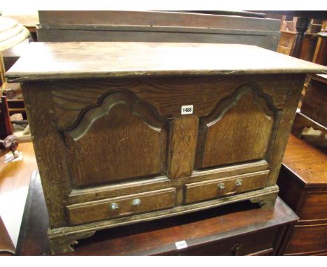An 18th century oak coffer bach with rising lid, the front elevation enclosed by two shaped and fielded panels over two friez