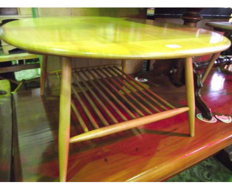 A vintage Ercol light elm and beechwood occasional table of oval form raised on four turned tapered and splayed legs united b