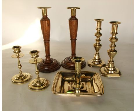 A pair of antique brass candlesticks with a further smaller pair, a brass chamber stick together with a pair of turned oak ca