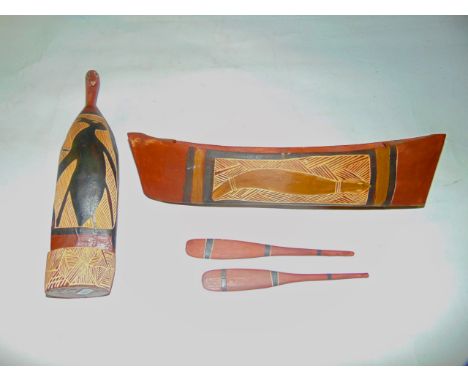 An Australian Aboriginal stained, incised and painted timber model of a canoe with two associated paddles, 40cm long approx t