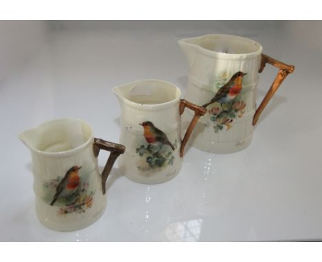 A set of three graduated Royal Worcester jugs with coopered style moulding and rustic handles and painted decoration of robin