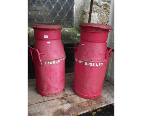 A pair of vintage cast iron two handled milk churns with raised lettering to band, Cadbury Bros Ltd, complete with caps and l