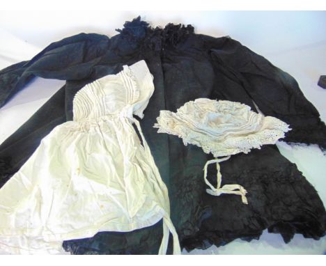 A black stitched suitcase containing vintage clothing to include a black woollen jacket etc