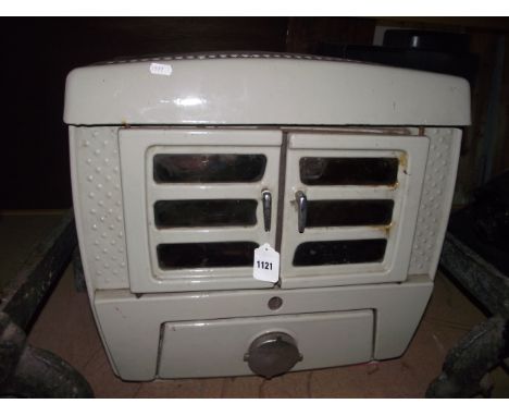 A vintage cast iron and cream enamelled stove enclosed by a pair of doors
