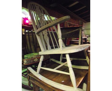 A Windsor style high hoop and stick back rocking chair with pierced wheel splat over a saddle shaped seat, splayed turned sup