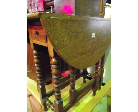 A small old English style oak oval drop leaf gateleg occasional table with frieze drawer raised on eight turned bobbin and bl
