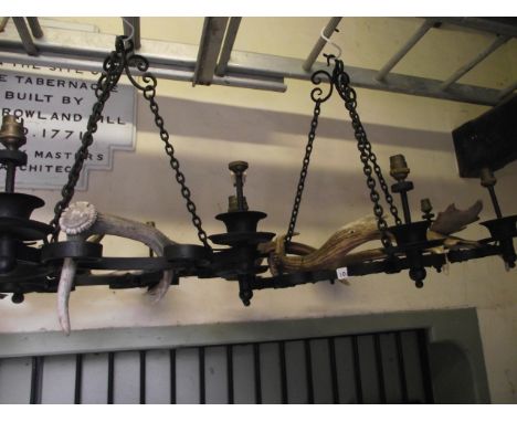 A pair of baronial style iron work hanging electroliers/ceiling lights, the scrollwork frame with six light sockets and entwi