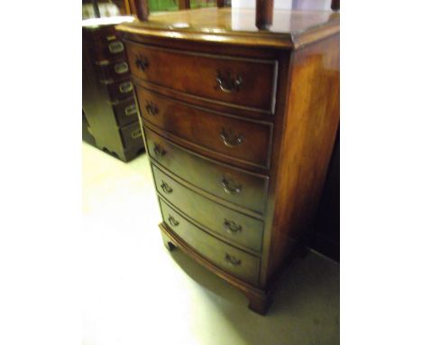 A small walnut veneered and bow fronted bedroom chest in the Georgian style fitted with five long graduated drawers raised on