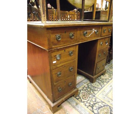 A small 19th century mahogany kneehole writing desk fitted with an arrangement of 9 drawers with brass ring handles and inset