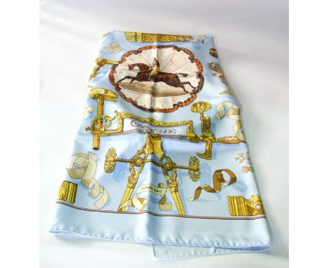 A boxed silk scarf marked Hermes Paris, centred with a stylised jockey and mount, upon a sky blue ground enclosed with studie