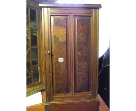 A late Victorian walnut bedside cupboard with moulded plinth and enclosed by a twin rectangular moulded panelled door with bu