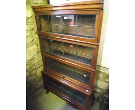 An early 20th century freestanding four sectional library bookcase, graduated and enclosed by up and over leaded light panell