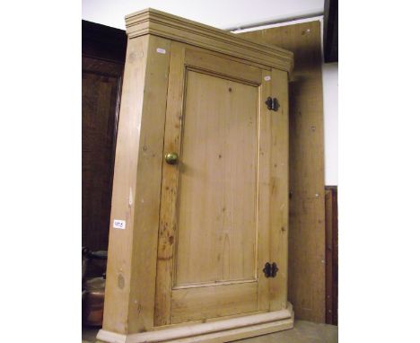 A stripped pine hanging corner cupboard enclosed by a rectangular moulded panelled door, the interior fitted with a central s