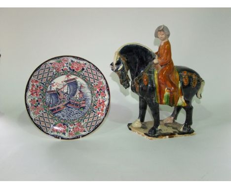 An oriental pottery model of a equestrian figure in the Tang style with blue, ochre and green glazed finish and raised on an 