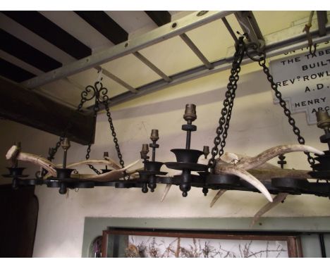 A pair of baronial style iron work hanging electroliers/ceiling lights, the scrollwork frame with six light sockets and entwi