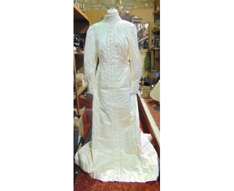 An ivory wild silk Wedding dress and train, with high collar, leg of mutton sleeves and self covered buttons to front a brigh