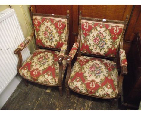 A pair of 19th century walnut open armchairs with carved framework and hand worked tapestry seats and backs on turned and flu
