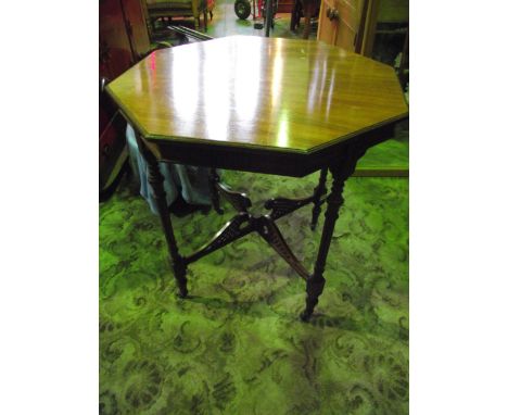 A late Victorian walnut occasional table of octagonal form with carved foliate and further detail and raised on four slender 