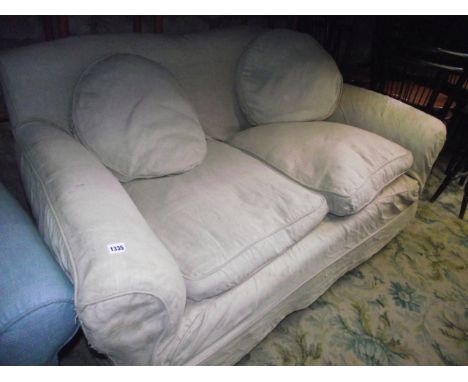 An Edwardian two seat sofa, the deep seat flanked by scrolled arms and shaped back with later loose covers