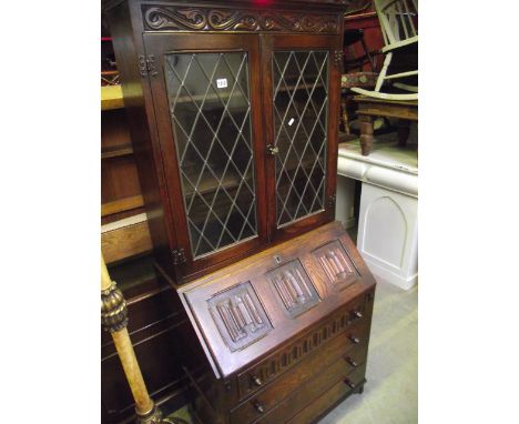 A reproduction oak bureau bookcase, probably Jaycee or Old Charm, the bookcase enclosed by a pair of diamond quarry leaded li